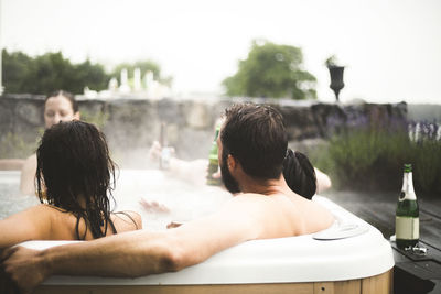 Male and female friends enjoying in hot tub during weekend getaway