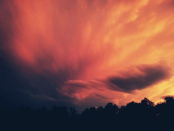 High section of silhouette trees against orange cloudy sky