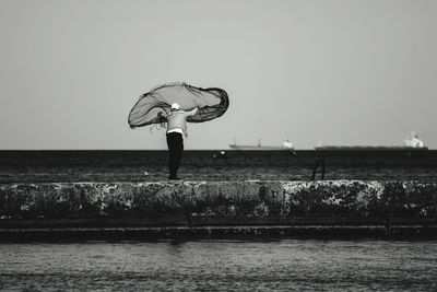 Man fishing in sea against clear sky