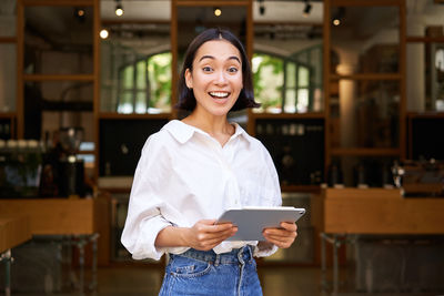 Portrait of young woman standing in cafe