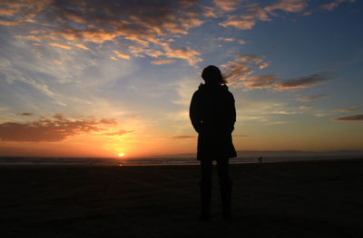 Silhouette woman standing at beach during sunset