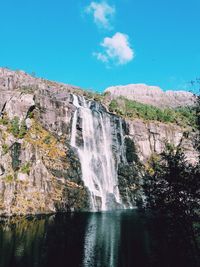 Scenic view of waterfall against sky