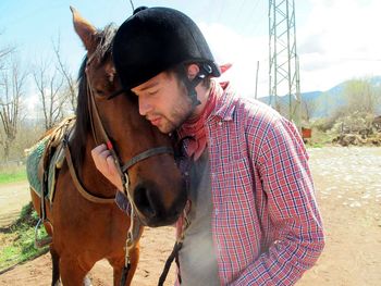 Portrait of young man with horse on field