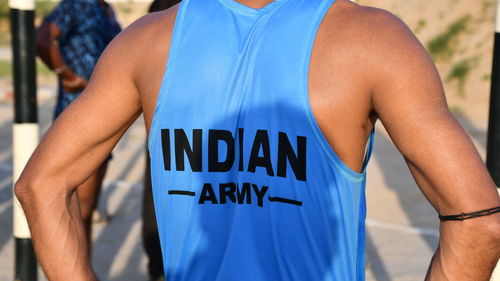 Midsection of man holding hands standing against blue wall