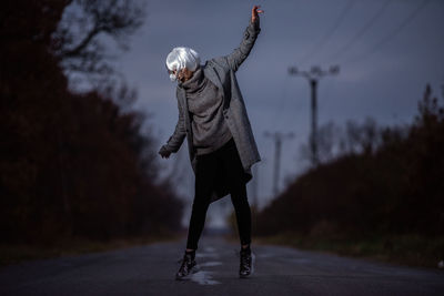 Woman with umbrella on road against sky