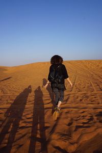 Rear view of woman walking in desert