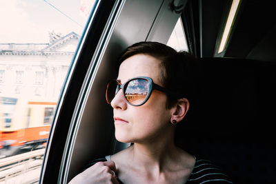 Woman wearing sunglasses by window in train