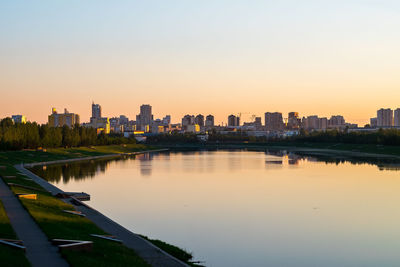 Scenic view of river by buildings against sky during sunset