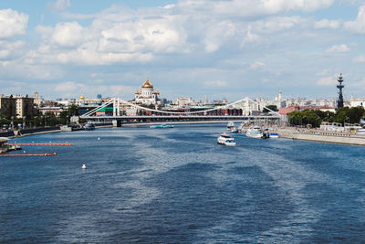 View of buildings by river against cloudy sky