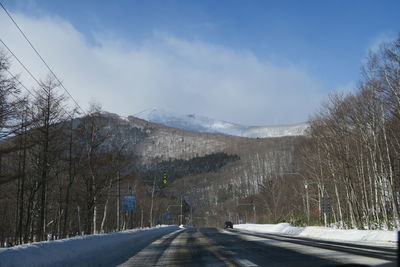 Road amidst trees against sky during winter