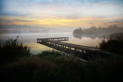 Bridge over river against sky during sunset