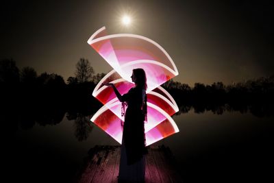 Pink umbrella by lake against sky during sunset