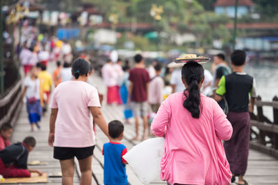 Rear view of people walking on street in city