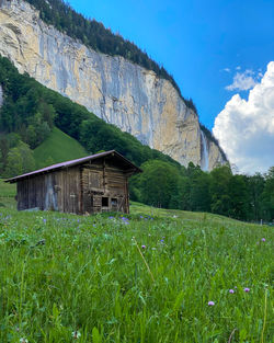 House on field by mountain against sky