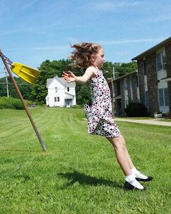 Side view of cute girl with arms outstretched playing lawn