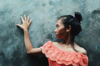 Thoughtful woman standing against wall