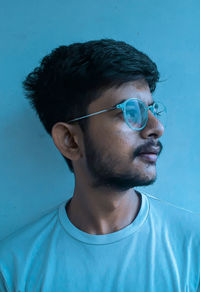 Man wearing eyeglasses against blue wall