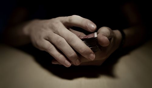 Cropped hands of man holding cards on table