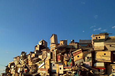 Low angle view of birdhouses against blue sky