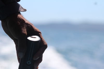 Close-up of hand holding sea against sky