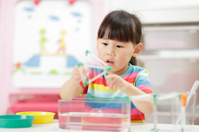 Cute girl playing with building blocks at classroom