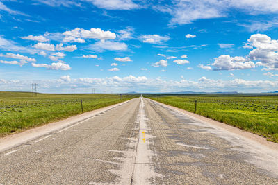 Road amidst field against sky