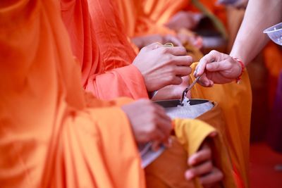 Cropped image of woman giving food to monks