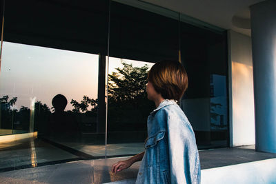 Side view of woman looking through window