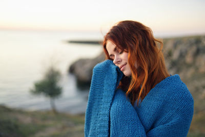 Beautiful woman looking at sea against sky during sunset