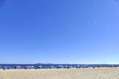 Panoramic view of people on landscape against clear blue sky