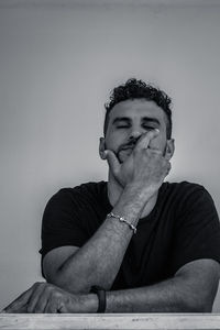 Portrait of young man sitting against wall