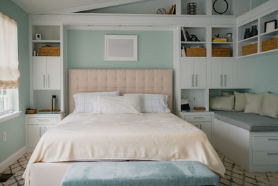 Bright bedroom interior with built in bookshelves and bench