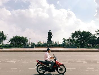 Man riding bicycle on street against sky