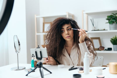 Young woman using mobile phone while sitting at home