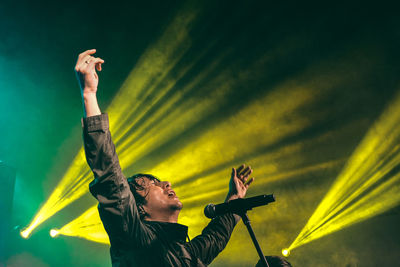 Low angle view of man with arms raised against sky