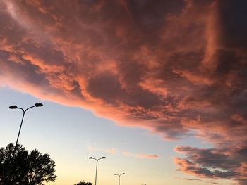 Low angle view of street lights against orange sky