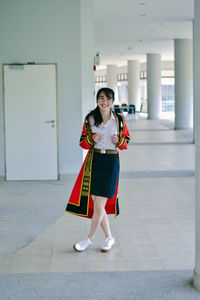 Portrait of a smiling young woman standing against tiled floor