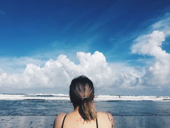 Rear view of woman at beach against sky