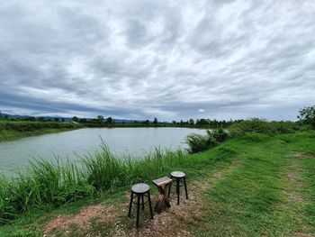 Scenic view of field by lake against sky