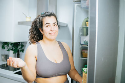 Portrait of smiling woman by refrigerator