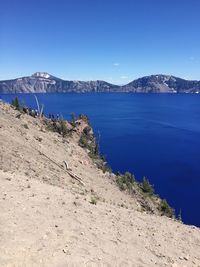 Scenic view of lake and mountains against clear blue sky