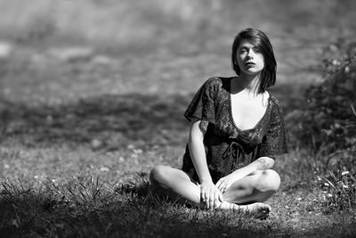 Portrait of young woman sitting on field