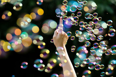 Cropped hand of woman touching bubbles