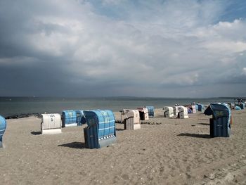 Hooded chairs on beach against sky