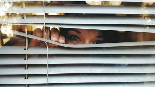 Portrait of woman looking through blinds