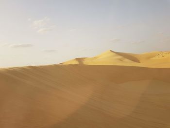 Sand dunes in desert against sky