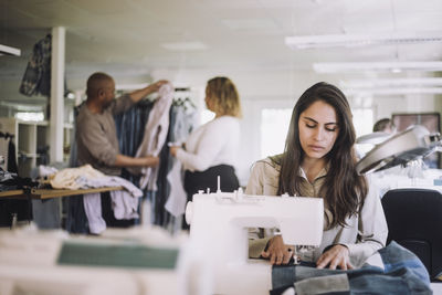 Female designer professional working on sewing machine at workshop