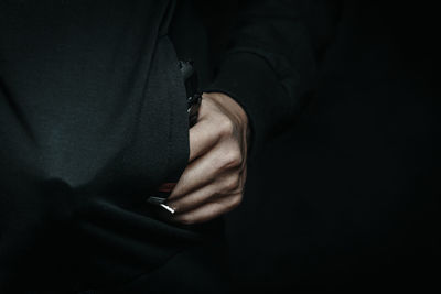 Midsection of man holding hands against black background