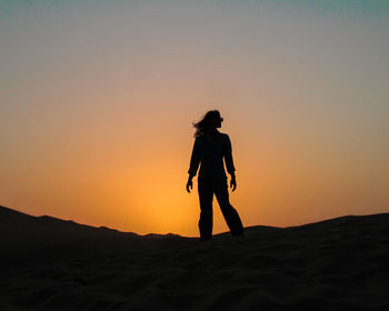 Silhouette woman standing on mountain against clear sky during sunset