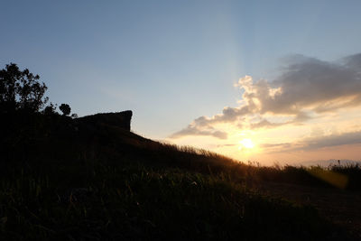 Scenic view of silhouette field against sky during sunset